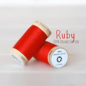 May include: Two spools of red thread labeled "Ruby 100% Organic Cotton".