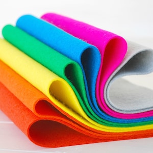 May include: A stack of colourful felt sheets in rainbow order, starting with orange and ending with grey. The felt is rolled up and the ends are visible.
