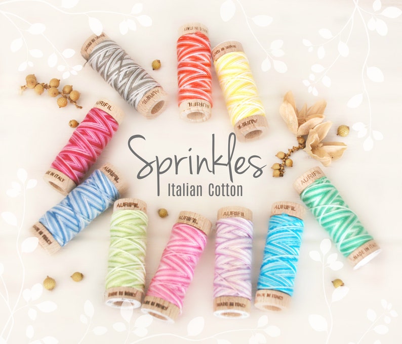 May include: A collection of colorful Aurifil Italian cotton thread spools. The spools are in various colors, including red, pink, blue, yellow, and green. The text "Sprinkles Italian Cotton" is displayed in the image.