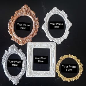 May include: Five ornate picture frames in various shapes and colors. The frames include oval, diamond, and rectangular designs, with metallic finishes in gold, silver, and bronze. Each frame has a black space with the text "Your Photo Here".