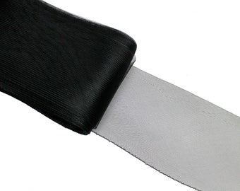 Può includere: Nastro di tulle nero con una superficie leggermente strutturata. Il nastro è piegato a metà, mostrando il rovescio del tessuto.