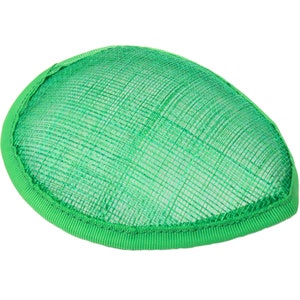 May include: A bright green, oval-shaped fascinator hat. The hat features a woven, mesh-like top and a solid green ribbon trim around the edge. The accessory is designed for formal events and adds a pop of color.