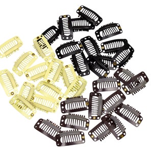 Puede incluir: Un gran grupo de pinzas para el pelo en negro, marrón y beige. Las pinzas son todas del mismo tamaño y forma, y están dispuestas en un patrón aleatorio.