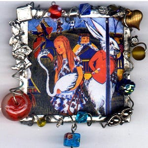 May include: A silver-toned charm necklace featuring a vintage book illustration of Alice in Wonderland with a white swan, a red-clad Mad Hatter, and a white rabbit. The charm is surrounded by colorful glass beads and a gold-toned Alice in Wonderland figurine dangles from the bottom.