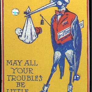 May include: A vintage illustration of a stork carrying a baby in a white blanket. The stork is wearing a red jacket, a blue bow tie, and a top hat. The illustration is on a yellow background with the text "MAY ALL YOUR TROUBLES BE LITTLE ONES". The illustration is attached to a silver baby carriage charm.