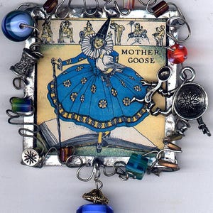 May include: A vintage illustration of Mother Goose, a woman in a blue dress and white ruff, holding a white goose, is framed in a silver metal frame. The frame is decorated with wire, beads, and charms, including a silver star charm and a charm of a person riding a goose.
