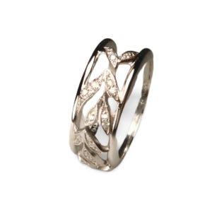 Peut inclure: Une bague en argent avec un motif de feuilles. La bague pr&eacute;sente des feuilles ajour&eacute;es, chacune orn&eacute;e de petites pierres scintillantes. L'anneau est lisse et poli, cr&eacute;ant un contraste avec les feuilles textur&eacute;es.