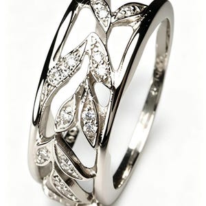 Peut inclure: Une bague en argent avec un motif de feuilles. La bague pr&eacute;sente des d&eacute;coupes en forme de feuilles, chacune orn&eacute;e de petites pierres pr&eacute;cieuses scintillantes. L'anneau est lisse et poli, cr&eacute;ant un contraste avec les feuilles textur&eacute;es.