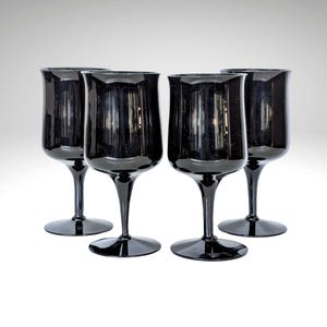 May include: Set of four black wine glasses with a wide bowl and a long stem. The glasses are made of clear glass and have a dark, almost black, tint.