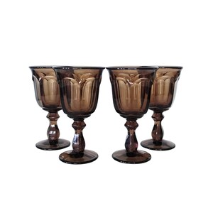 May include: Set of four brown glass stemmed goblets with a fluted design.