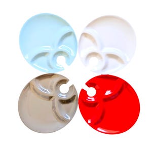 May include: Four colorful wine glass holders in blue, white, clear, and red. Each holder is round with a slot for the wine glass stem and three small compartments for snacks or dips. The holders are made of a glossy, smooth material.