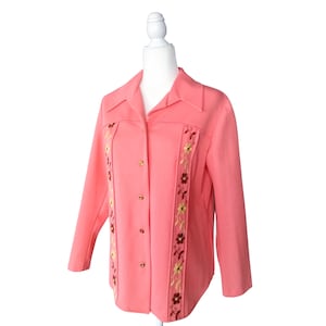 May include: A pink button-up jacket with long sleeves and embroidered floral details on the front.