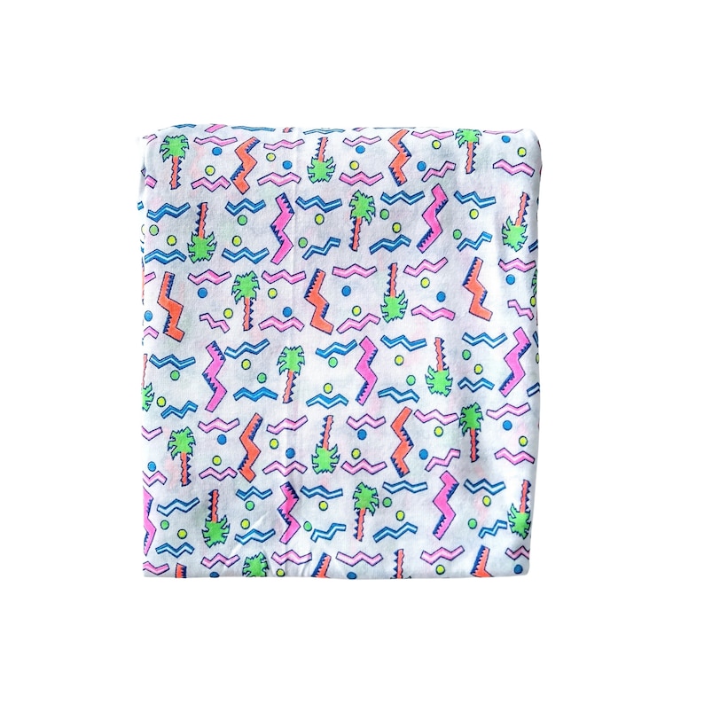 May include: White fabric with a repeating pattern of pink, blue, green, and orange palm trees, zigzags, and dots.