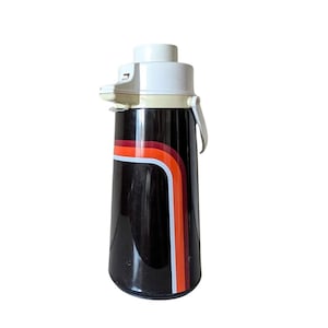 May include: A vintage black thermos with a white top and handle. The thermos features a retro design with orange, red, and white stripes. The thermos is approximately 12 inches tall.