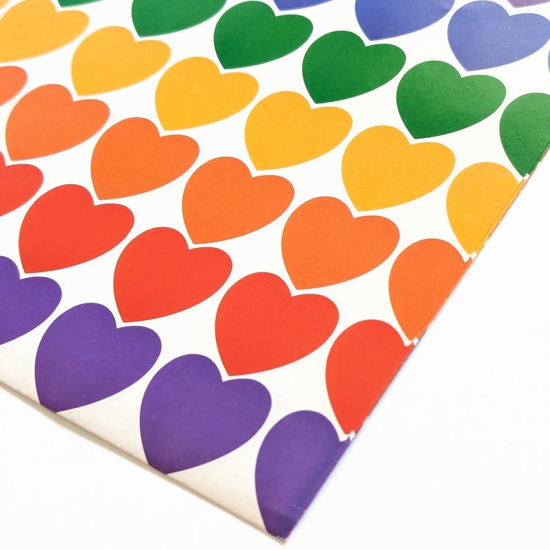 Pu&ograve; includere: Un foglio di carta con un motivo ripetuto di cuori colorati in rosso, arancione, giallo, verde, blu e viola. I cuori sono disposti in file diagonali su uno sfondo bianco. Un design vivace e allegro.