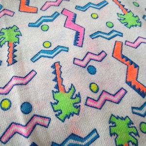 May include: White fabric with a colorful geometric pattern. The pattern includes zigzags, waves, and circles in pink, blue, green, and orange.