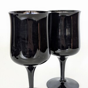 May include: Two black glass wine goblets with a wide bowl and a long stem.
