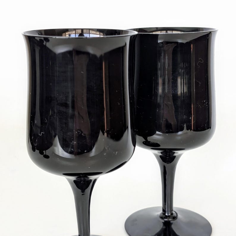May include: Two black glass wine goblets with a wide bowl and a long stem.