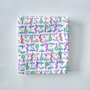 May include: White fabric with a repeating pattern of pink, blue, green, and orange palm trees, zigzags, and wavy lines.