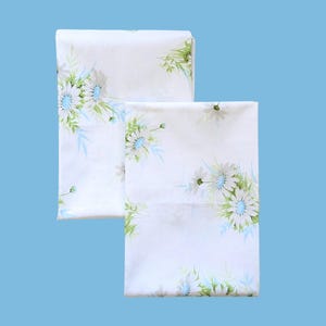 May include: A white ceramic mug with a black handle and the text "But First, Coffee" in a bold, black font. The mug is set against a blurred background, suggesting a cozy setting. The mug appears to be approximately 4 inches tall.