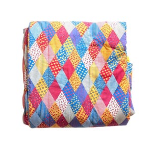 May include: A folded quilt featuring a repeating diamond pattern in various colors including red, yellow, blue, and white. The fabric segments display diverse small-scale prints such as floral motifs, thin stripes, and checkered gingham patterns.