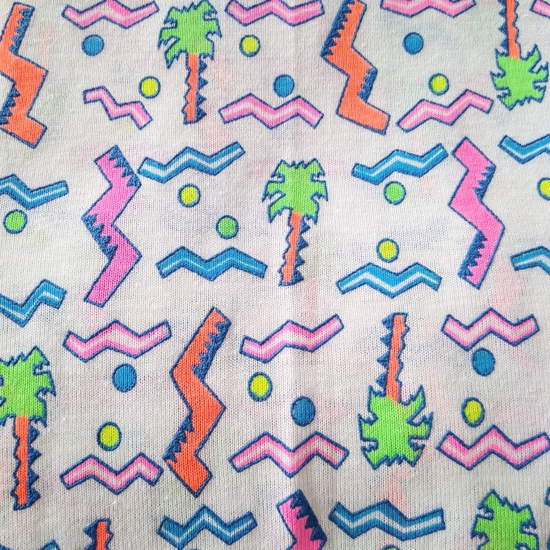 May include: A white fabric with a repeating pattern of pink, blue, green, and orange geometric shapes. The pattern includes zigzags, waves, and palm trees.