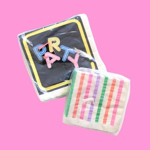 May include: Two packages of party napkins. One package has the word "PARTY" in colorful letters on a black background with a yellow border. The other package has vertical stripes in various colors.
