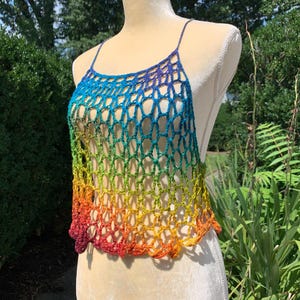 May include: A sleeveless crochet top featuring an open net pattern and a vibrant rainbow gradient color scheme that transitions from deep purple and blue at the neckline down through green and yellow to a bright orange and red at the hemline.