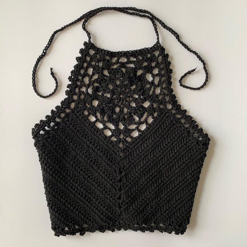 Puede incluir: Top negro de crochet con tirantes y un delicado patr&oacute;n floral. El top tiene un cierre de nudo en el cuello y una longitud recortada.