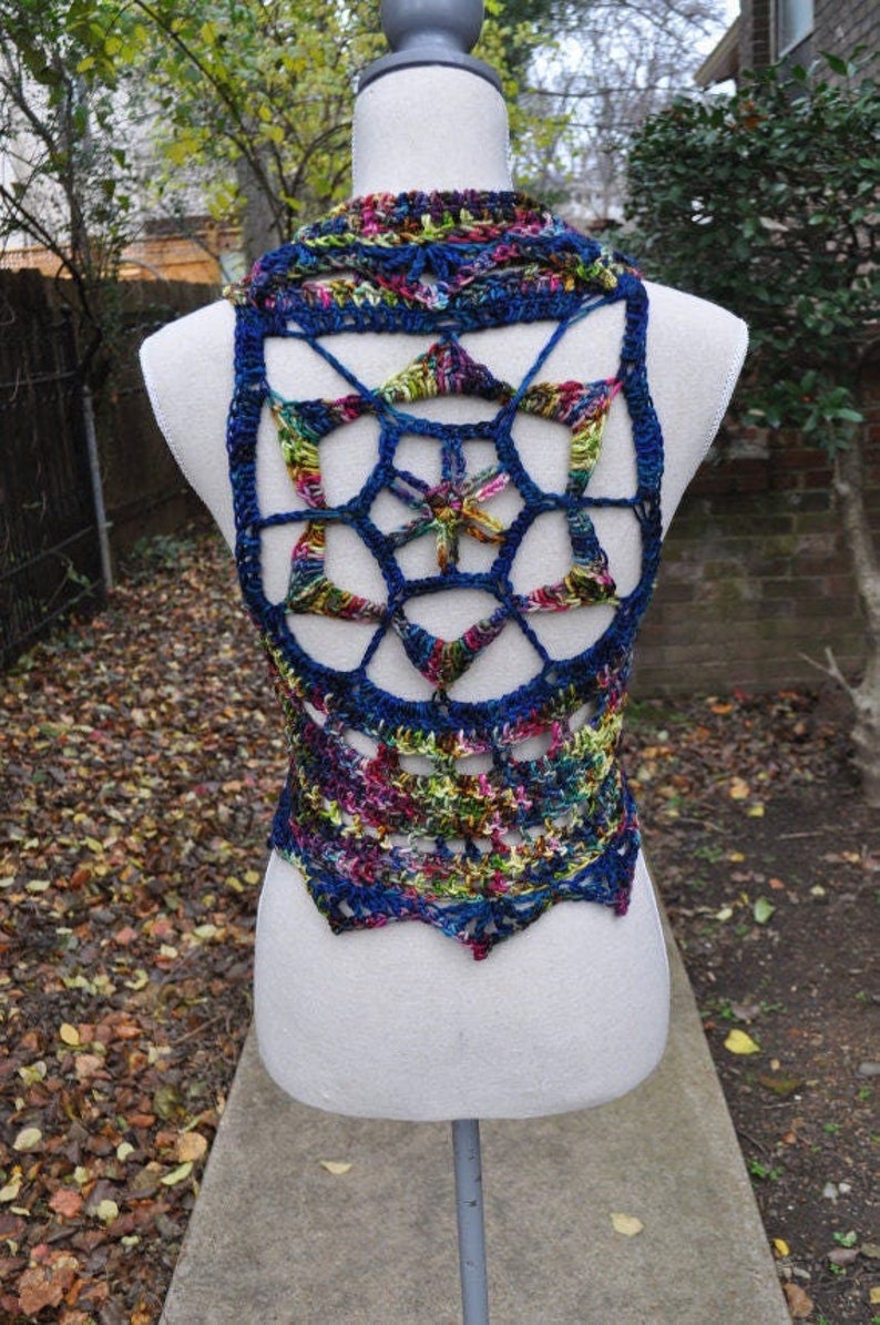 May include: A crocheted vest with a colorful, geometric design. The vest is made with a blue, green, and pink yarn and has a large, openwork pattern on the back.