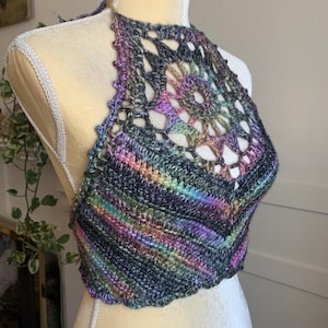 May include: A multi-colored crochet halter top with a large, openwork design in the center. The top is made with a variegated yarn that features shades of black, purple, green, and blue.