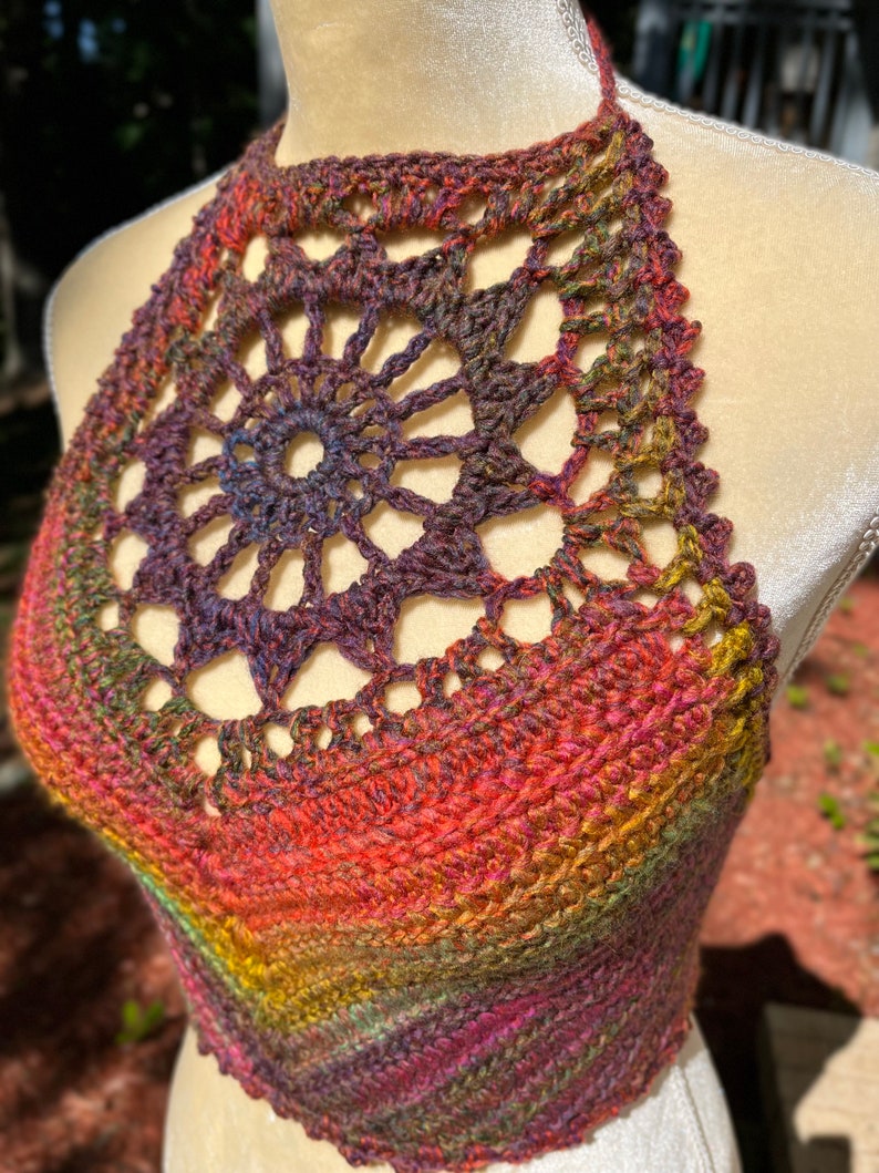 May include: A crocheted halter top with a colorful ombre design. The top features a large, openwork circle in the center.