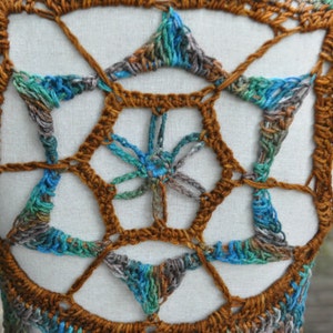 May include: A crocheted vest with a geometric pattern in shades of brown, blue, and green.