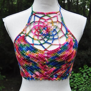 Puede incluir: Un top halter de crochet colorido con un diseño de telaraña en la espalda. El top está hecho con una variedad de colores, incluyendo rosa, azul, verde y amarillo.