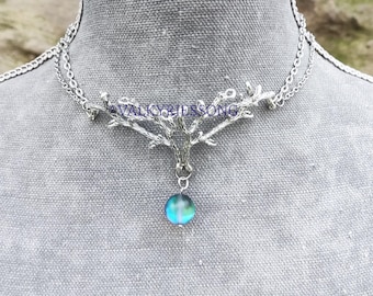 May include: Silver necklace with a branch design and a blue iridescent glass pendant.