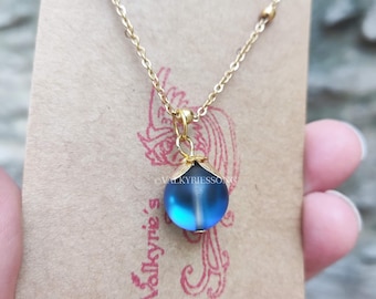 May include: A gold chain necklace with a blue glass pendant. The pendant is round and has a slight shimmer to it.
