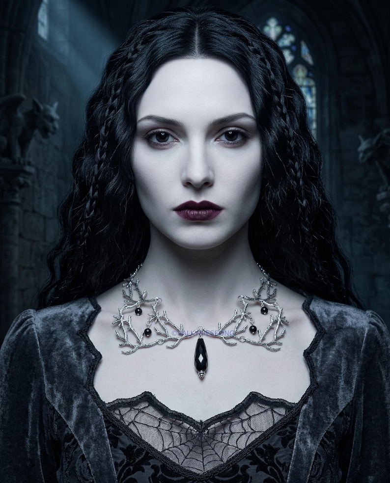 May include: A woman with pale skin and dark hair wears a silver necklace with black accents and a large black pendant. She is dressed in a dark velvet gown with lace detailing. The background is a gothic-style interior with gargoyles.