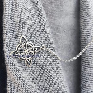 May include: A silver Celtic knot pendant on a silver chain. The pendant is a traditional Irish design with a four-leaf clover in the center.