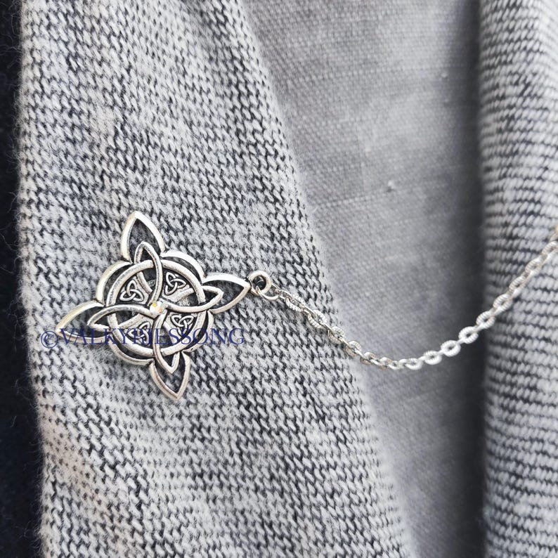 May include: A silver Celtic knot pendant on a silver chain. The pendant is a traditional Irish design with a four-leaf clover in the center.