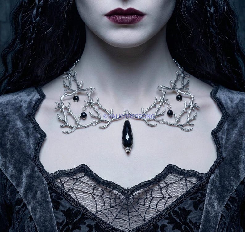 Handmade silver metal branch necklace with a faceted black onyx teardrop pendant. The intricate gothic fantasy design features silver-toned coral or twig-like structures adorned with small black gemstone beads, creating a statement nature-inspired, ethereal gothic look.