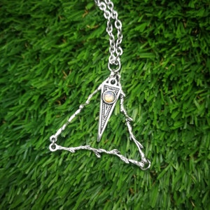 May include: A silver necklace with a triangular pendant featuring a small, round, yellow gemstone. The pendant is made of twisted wire and has a delicate, intricate design.