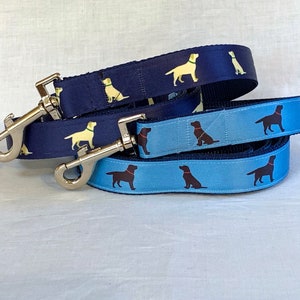 May include: Two dog leashes, one blue and one navy blue, with a silver clip. Both leashes feature a repeating pattern of Labrador Retriever silhouettes.