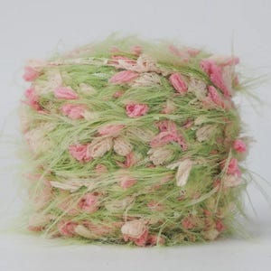 Pode incluir: Novel de fio texturizado em tons de verde claro, rosa e creme. O fio tem uma apar&ecirc;ncia fofa e difusa com pequenos detalhes em forma de flor. Ideal para projetos de tric&ocirc; ou croch&ecirc;.