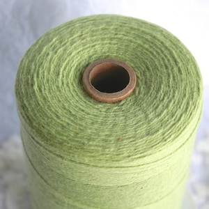May include: A spool of light green thread wound around a cardboard tube.