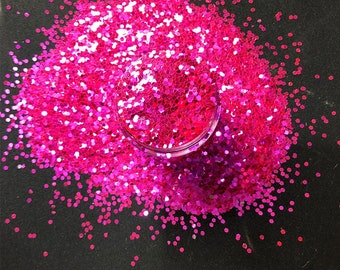 May include: A close-up of a pile of bright pink glitter, with some of the glitter spilling out of a clear container.