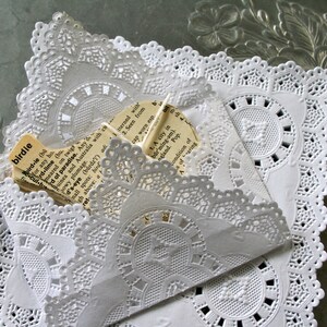 May include: White doilies with a lace pattern, layered on top of each other. A piece of paper with text is tucked inside the top layer. The text reads "birdie, ird-lebo for any ho, rd-lime (bu, meared on twigt, d of paradise. Any, cultu, Juines and Australia with ca, powy plumage. mall spots in, d's-eye (bards') adi, gh above a, ret, merned with, 2. Seen from, cap worn esp, 1. A city in, barming-om). naland. Pop. Condition of"