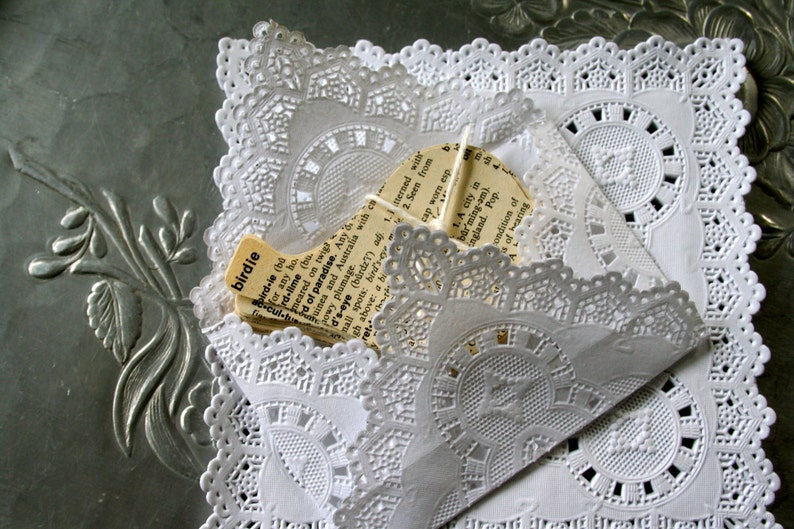 May include: A white doily with a lace pattern and a piece of paper with the word "birdie" and a definition of the word. The paper is partially obscured by the doily.