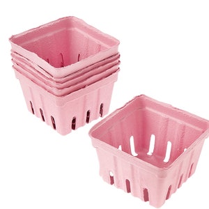 May include: A stack of five pink paper berry baskets. The baskets are square and have a scalloped edge. The baskets have holes in the bottom for drainage. One basket is laying on its side.
