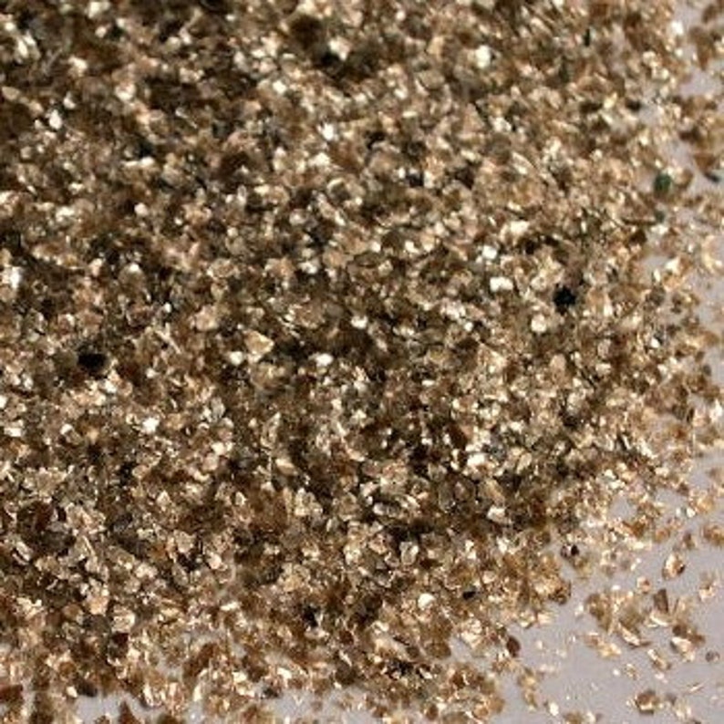 Peut inclure: Gros plan sur un tas de paillettes de mica dor&eacute;es iris&eacute;es. Les paillettes sont petites et de forme irr&eacute;guli&egrave;re, avec une finition m&eacute;tallis&eacute;e chatoyante.