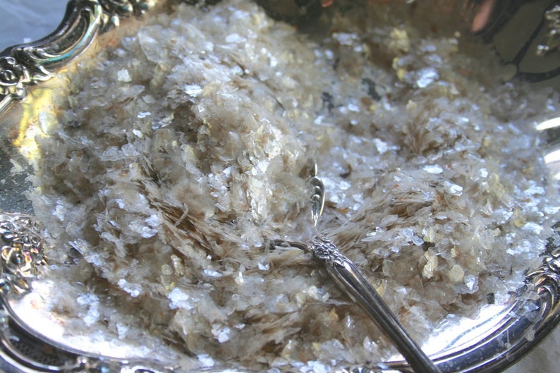 Peut inclure: Un plat de service en argent rempli de paillettes de mica iris&eacute;es. Une cuill&egrave;re en argent repose sur les paillettes.